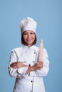 Professional positive asian cook standing with arm crossed holding kitchen rolling pin