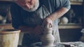 professional potter creating jar from brown clay in workplace using throwing-wheel. Traditional pottery, handmade Royalty Free Stock Photo