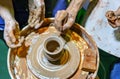 Professional potter makes a pot on a pottery wheel and teaches a pupil. Hands of a potter Royalty Free Stock Photo