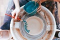 Professional potter works on painting plates in the workshop. Woman paints a ceramic plate with a brush and blue paint Royalty Free Stock Photo