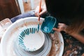 Professional potter works on painting plates in the workshop. Woman paints a ceramic plate with a brush and blue paint Royalty Free Stock Photo