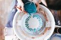 Professional potter works on painting plates in the workshop. Woman paints a ceramic plate with a brush and blue paint Royalty Free Stock Photo