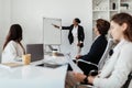 Professional presentation. Black businesswoman giving speech at corporate meeting, pointing at whiteboard