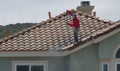 Professional pressure-washing a tile roof on a home