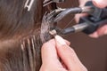 Professional process of hair extension for a woman with the help of artificial, in a beauty salon close up