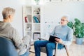 Professional psychotherapy. Male psychologist having session with male patient at mental health clinic, Taking Notes Royalty Free Stock Photo