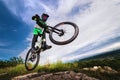 professional racer jumps on a bicycle against a blue cloudy sky. Sunny summer day. Low angle view of a man on a mountain