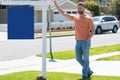 Professional realtor real estate agent with house for sale sign standing near residential property outside. Copy space. Royalty Free Stock Photo