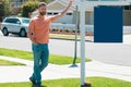 Professional realtor real estate agent with house for sale sign standing near residential property outside. Copy space. Royalty Free Stock Photo