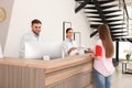 Professional receptionists working with patient at desk