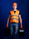 Professional repairman concept. Man in helmet, hard hat holds toolbox and suitcase with tools, blue background. Worker Royalty Free Stock Photo