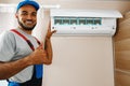 Professional repairman installing air conditioner in a room