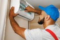 Professional repairman installing air conditioner in a room