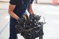 Professional repairman works with broken automobile engine