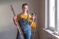 Professional repairwoman doing a home renovation. Female posing and holding a drill and level.