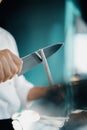 Professional restaurant kitchen, male chef sharpening a knife Royalty Free Stock Photo