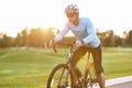 Professional road bicycle racer in sportswear and protective helmet standing on the road at sunset, ready to ride. Man Royalty Free Stock Photo