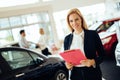 Professional saleswoman working in car dealership Royalty Free Stock Photo