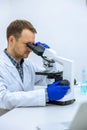 Scientist man doing chemical experiment, making analyzing, looking sample under microscope Royalty Free Stock Photo