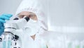Professional scientist in protective gear is using microscope in a laboratory setting, close-up of researcher. Science Royalty Free Stock Photo