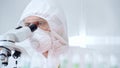 Professional scientist in protective gear is using microscope in a laboratory setting, close-up of researcher. Science Royalty Free Stock Photo