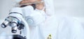 Professional scientist in protective gear is using microscope in a laboratory setting, close-up of researcher. Science Royalty Free Stock Photo