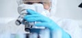 Professional scientist in protective gear is using microscope in a laboratory setting, close-up of researcher. Science Royalty Free Stock Photo