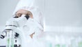 Professional scientist in protective gear is using microscope in a laboratory setting, close-up of researcher. Science Royalty Free Stock Photo