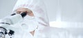 Professional scientist in protective gear is using microscope in a laboratory setting, close-up of researcher. Science Royalty Free Stock Photo