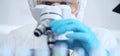 Professional scientist in protective gear is using microscope in a laboratory setting, close-up of researcher. Science Royalty Free Stock Photo