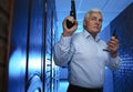 Professional security guard with gun and radio set in dark hallway