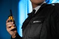 Professional security guard with portable radio set near window in dark room