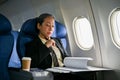 A senior Asian businesswoman focuses on reading business reports during the flight Royalty Free Stock Photo