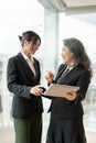 A professional senior Asian businesswoman is talking with a young colleague Royalty Free Stock Photo