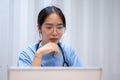 A professional and serious Asian female doctor is reading medical cases on her laptop Royalty Free Stock Photo