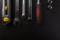 A composition of hand tools. Utility knife, combination wrenches and a socket set with ratchet on a black background