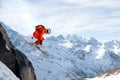 A professional skier makes a jump-drop from a high cliff against a blue sky leaving a trail of snow powder in the Royalty Free Stock Photo