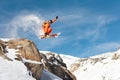 A professional skier makes a jump-drop from a high cliff against a blue sky leaving a trail of snow powder in the Royalty Free Stock Photo