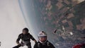 Professional skydivers jump from airplane make formation in cloudness sky.