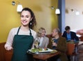 Professional smiling nippy with tray posing at table