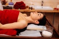 Peaceful dark-haired woman covered in red towel resting on wooden table