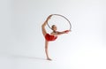 Professional sports. Artistic young gymnast with hula hoop practicing her performance on white background