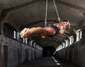 A professional sportsman with a beautiful muscular body trains on gymnastic rings in abandoned industrial building Royalty Free Stock Photo