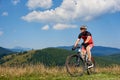 Professional sportsman cyclist in sportswear and helmet cycling a bike in high grass