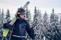 Male skier in goggles with professional ski equipment on his shoulders standing on slope top before skiing in mountains. Royalty Free Stock Photo