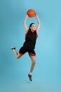 Professional sportswoman playing basketball on light blue background