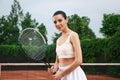 Professional sportswoman with tennis racket at court