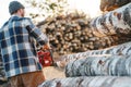 Professional strong lumberman wearing plaid shirt use chainsaw on sawmill