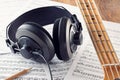 Professional studio headphones and bass guitar neck on music sheets background Royalty Free Stock Photo