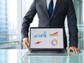 Businessman presenting financial charts and graphs on a laptop screen in office Royalty Free Stock Photo